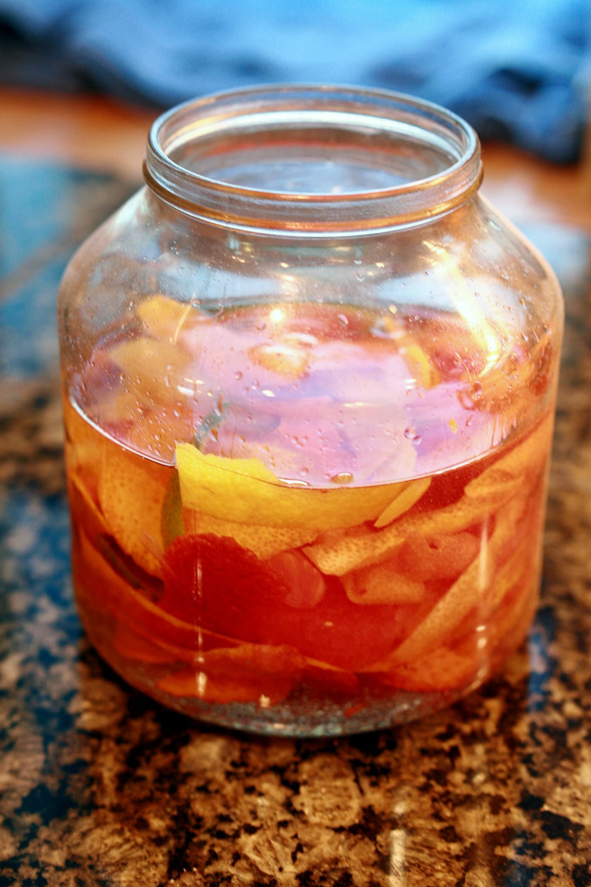 A large jar filled with citrus peels and rum.
