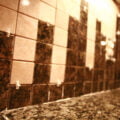 A close up view of a section of granite tile backsplash. The square tiles are held apart with little white spacers.