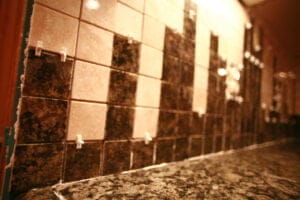 A close up view of a section of granite tile backsplash. The square tiles are held apart with little white spacers.