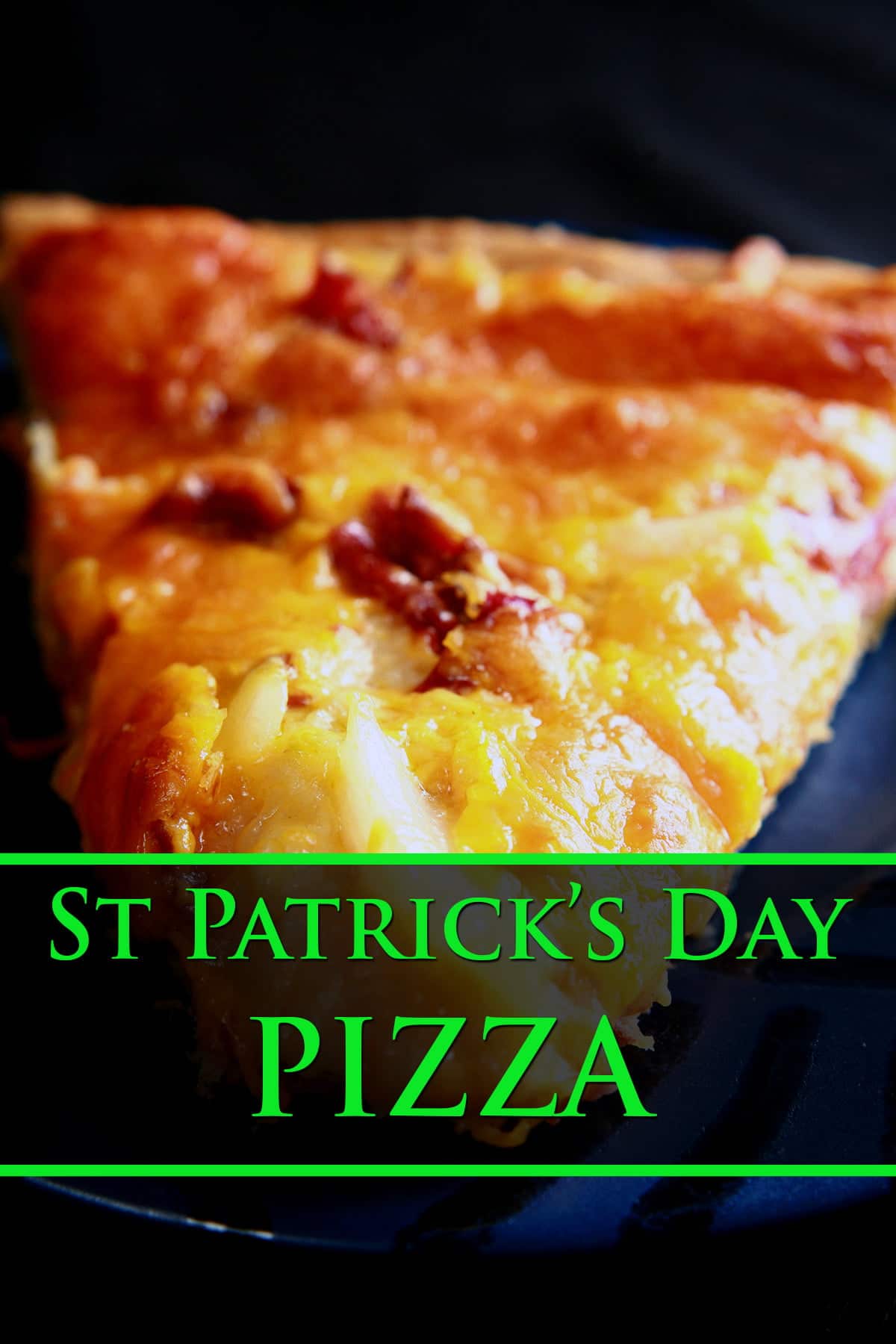 A slice of St Patrick's Day Pizza on a blue plate. Chunks of cabbage and corned beef are visible from under the cheese.