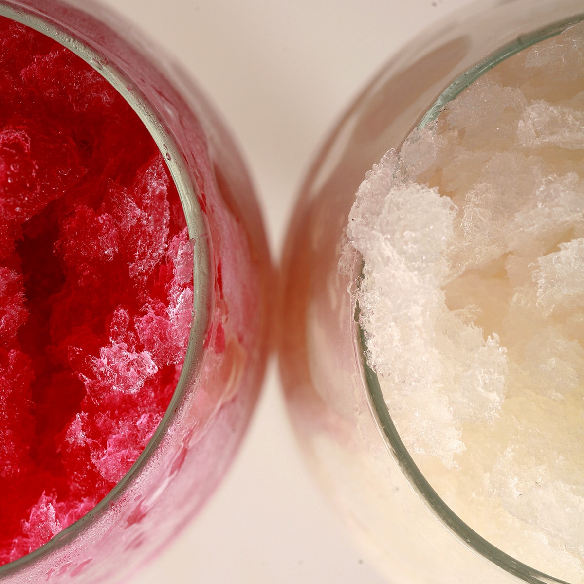 Two frosty wine glasses with wine slush in them - one is made with red wine, the other with white.