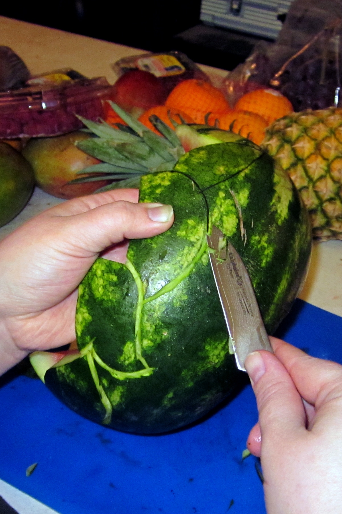 A paring knife is used to cut the edge of the caladium leaf design into the watermelon.