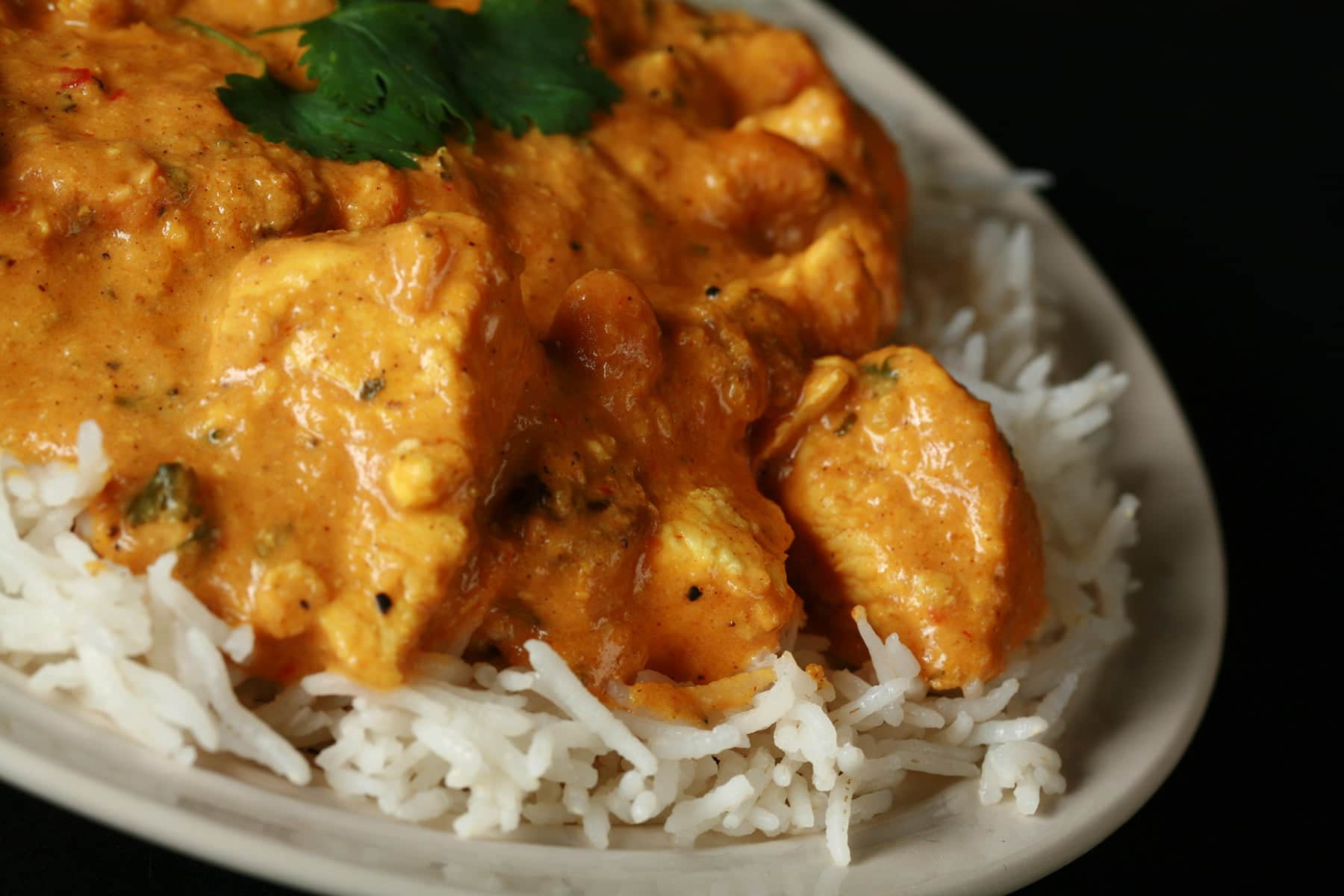 A plate with rice smothered in a creamy Chicken Shahi Korma.
