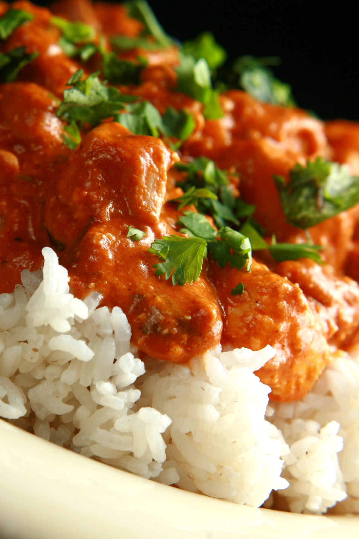 A close up view of Butter Chicken - Chicken in a  creamy tomato sauce, served over rice.