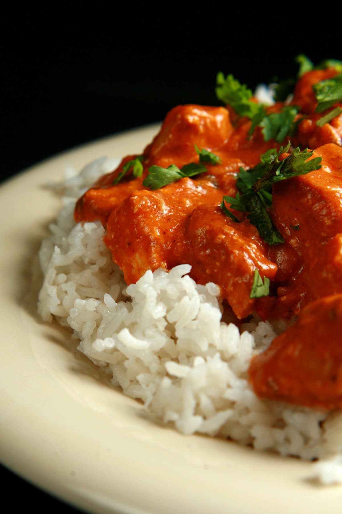 A close up view of Butter Chicken - Chicken in a  creamy tomato sauce, served over rice.