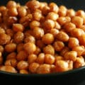 A shallow white and black bowl, piled high with roasted chickpeas.