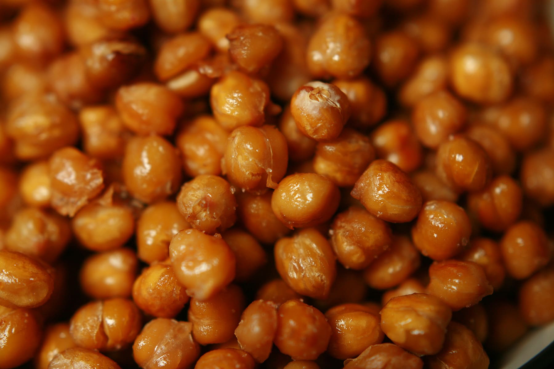 A shallow white and black bowl, piled high with roasted chickpeas.