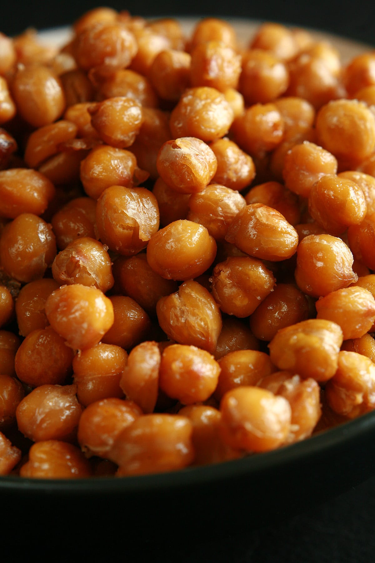 A shallow white and black bowl, piled high with roasted garbanzo beans.