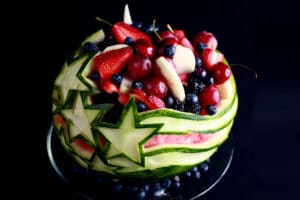 An Independence Day Watermelon Bowl. It is carved with a stars and stripes design, and filled with red, white, and blue fruit.