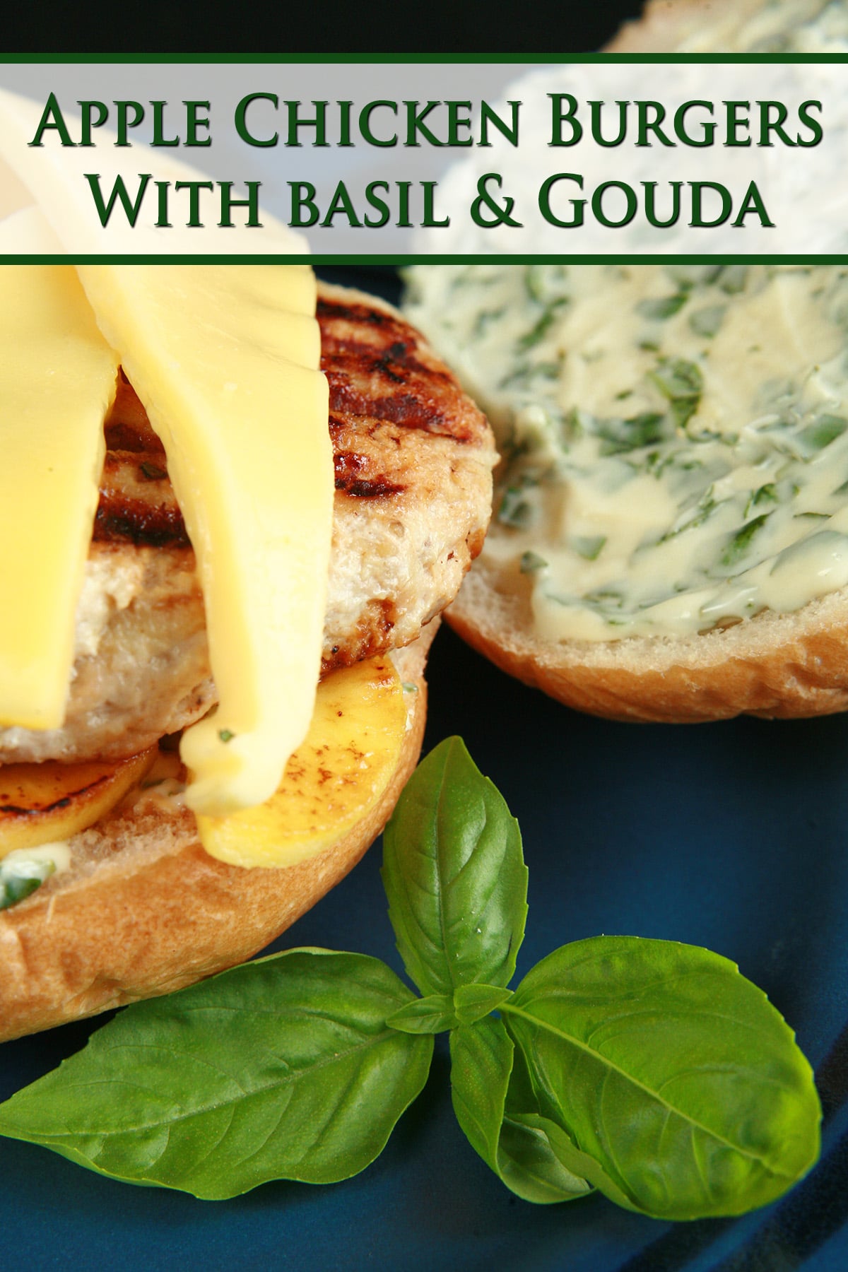 An apple chicken burger with slices of gouda cheese and spread with basil mayonnaise, on a blue plate.