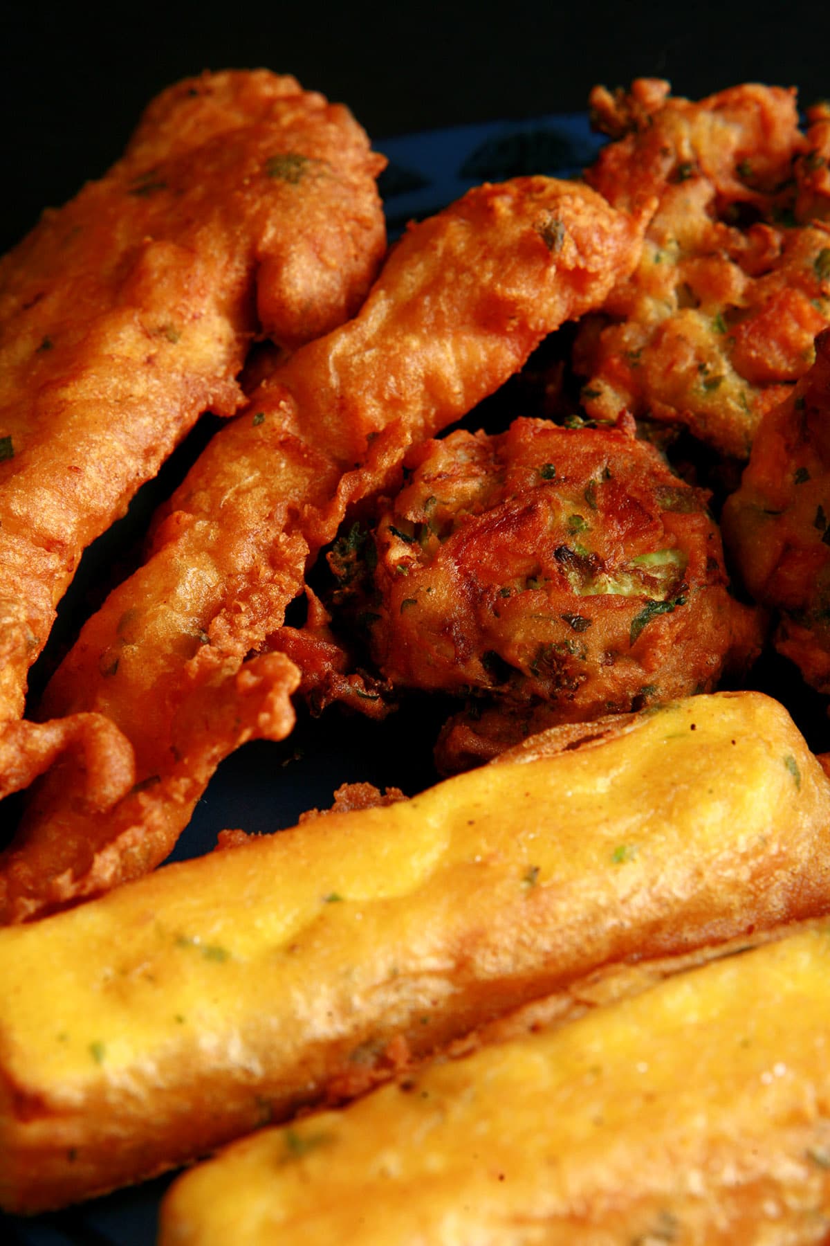 A close up view of a plate of several types of pakora - chicken, paneer and mixed vegetable pakoras.