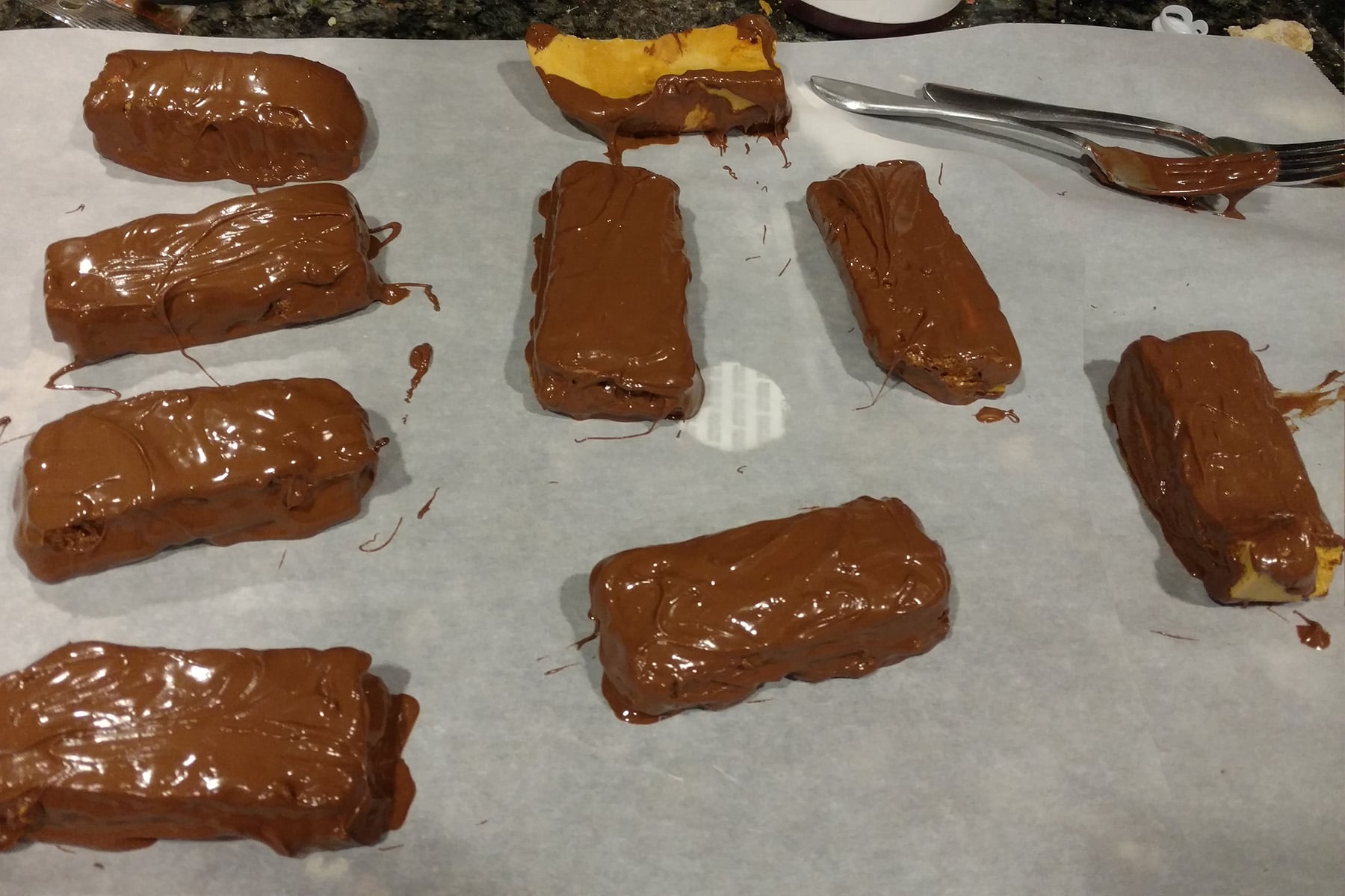 Freshly dipped bars of honeycomb toffee, coated in chocolate.