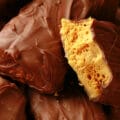 A small red plate is piled high woth homemade crunchie bars. One is broken in half to reveal the honeycomb toffee inside.