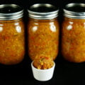 3 jars of Hoppy Dill Pickle Relish. It's a golden orange relish with flecks of dark green and red throughout. There is a small cup of the relish in front of the jars.