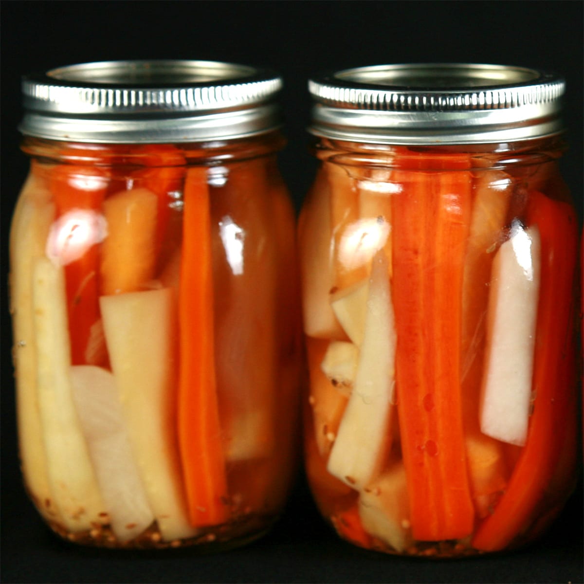 2 jars of mixed root vegetable pickles. Spears of carrot, parsnip, and turnip are visible.