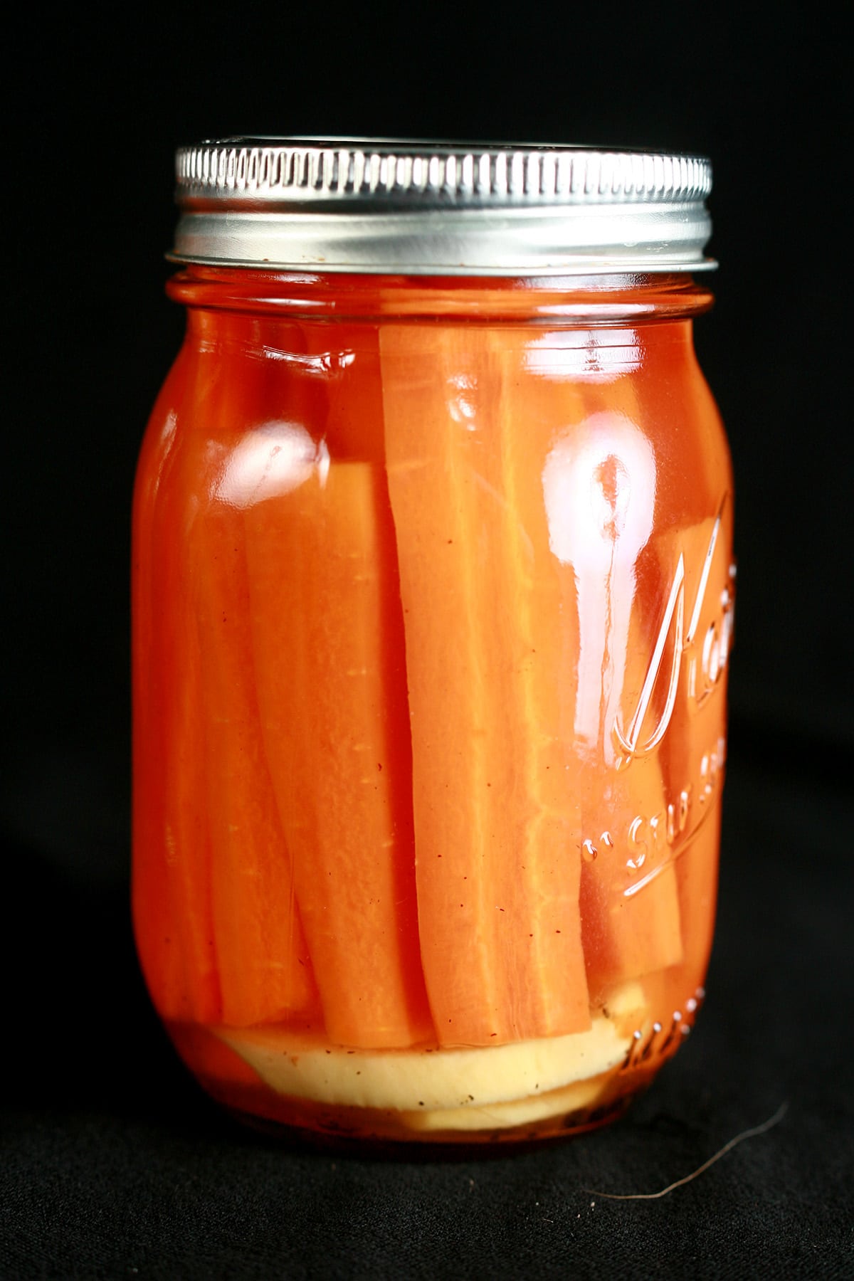 A jar of pickled carrots with fresh ginger.