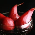 3 wine poached pears in a large, faceted goblet.