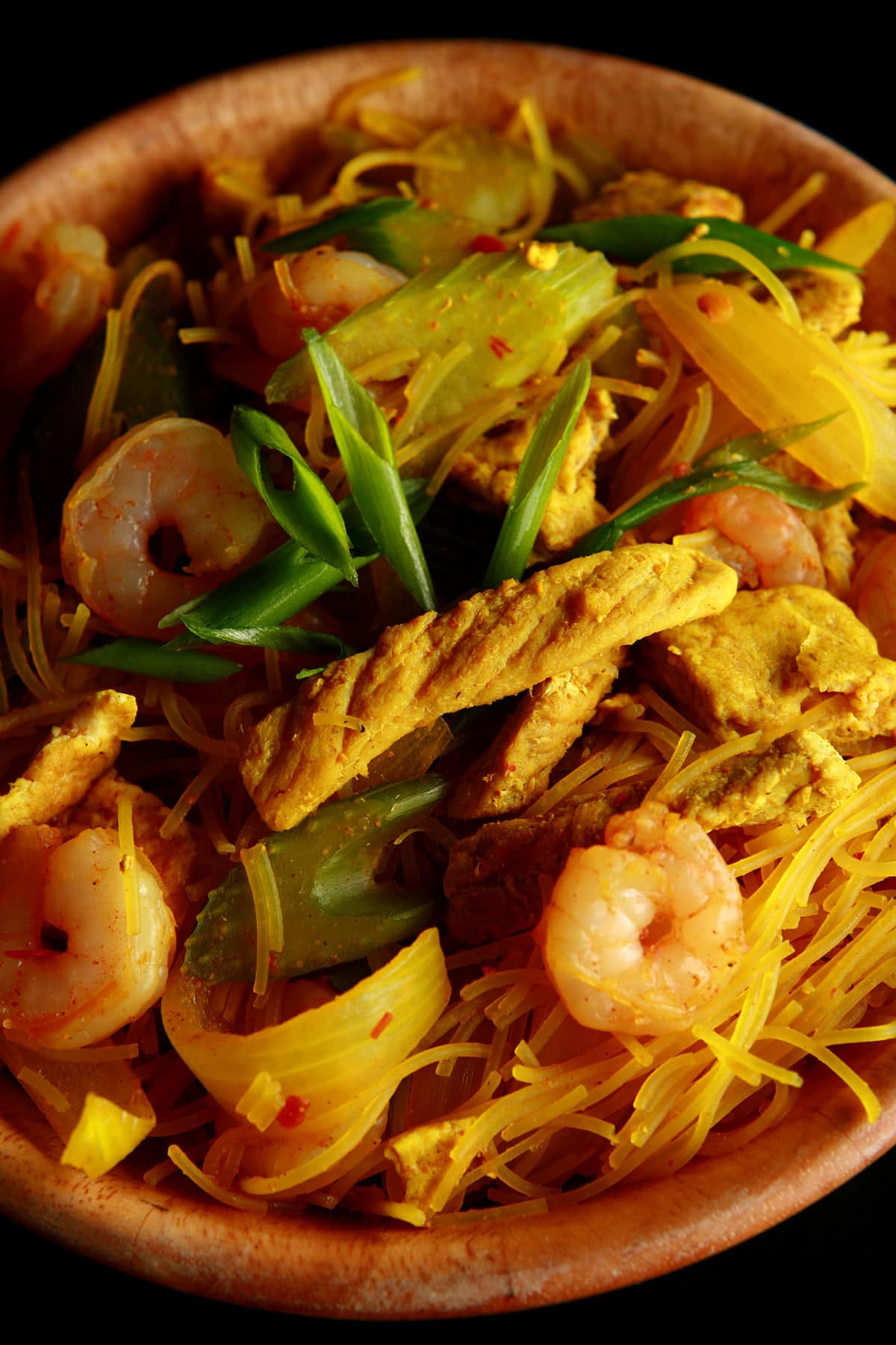 A large bowl of Singapore Mai Fan - curried vermacelli noodles with onion, celery, chicken, and shrimp visible throughout.