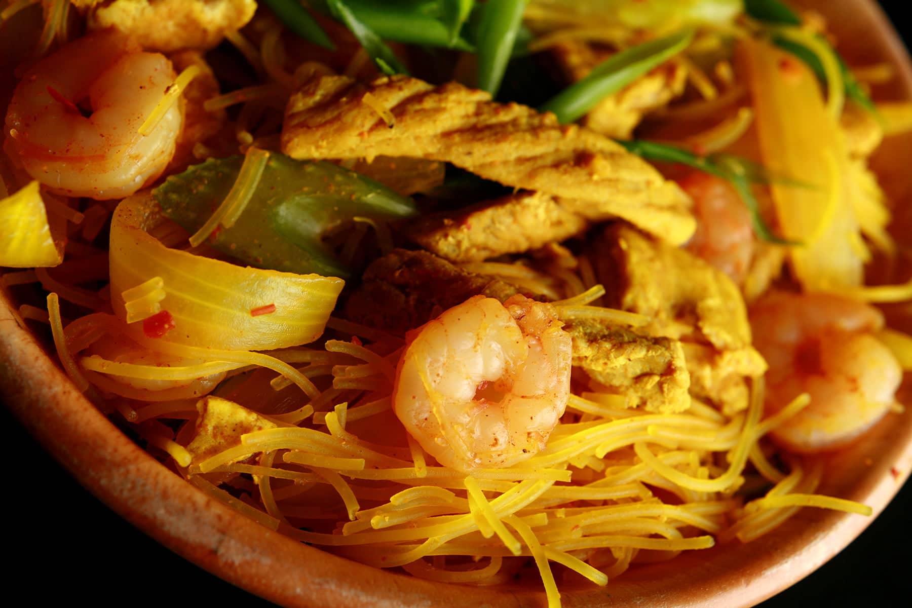 A large bowl of Singapore Mai Fan - curried vermacelli noodles with onion, celery, chicken, and shrimp visible throughout.