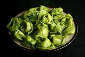 A plate of bright green spanakopita tortellini.