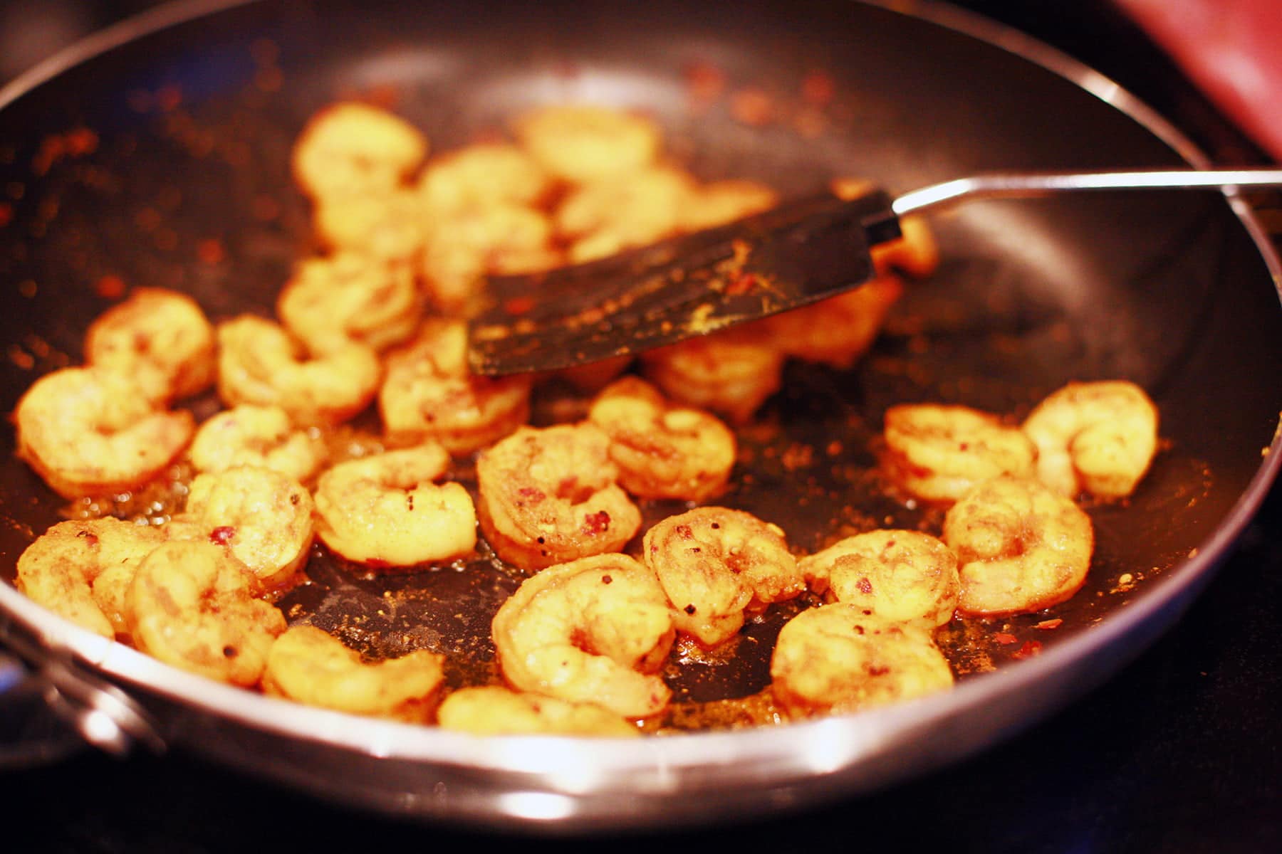 A close up view of curried shrimps being sauteed in a pan.