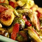 A pale green platter, mounded with roasted Brussels Sprouts. Chopped Bacon is visible throughout.