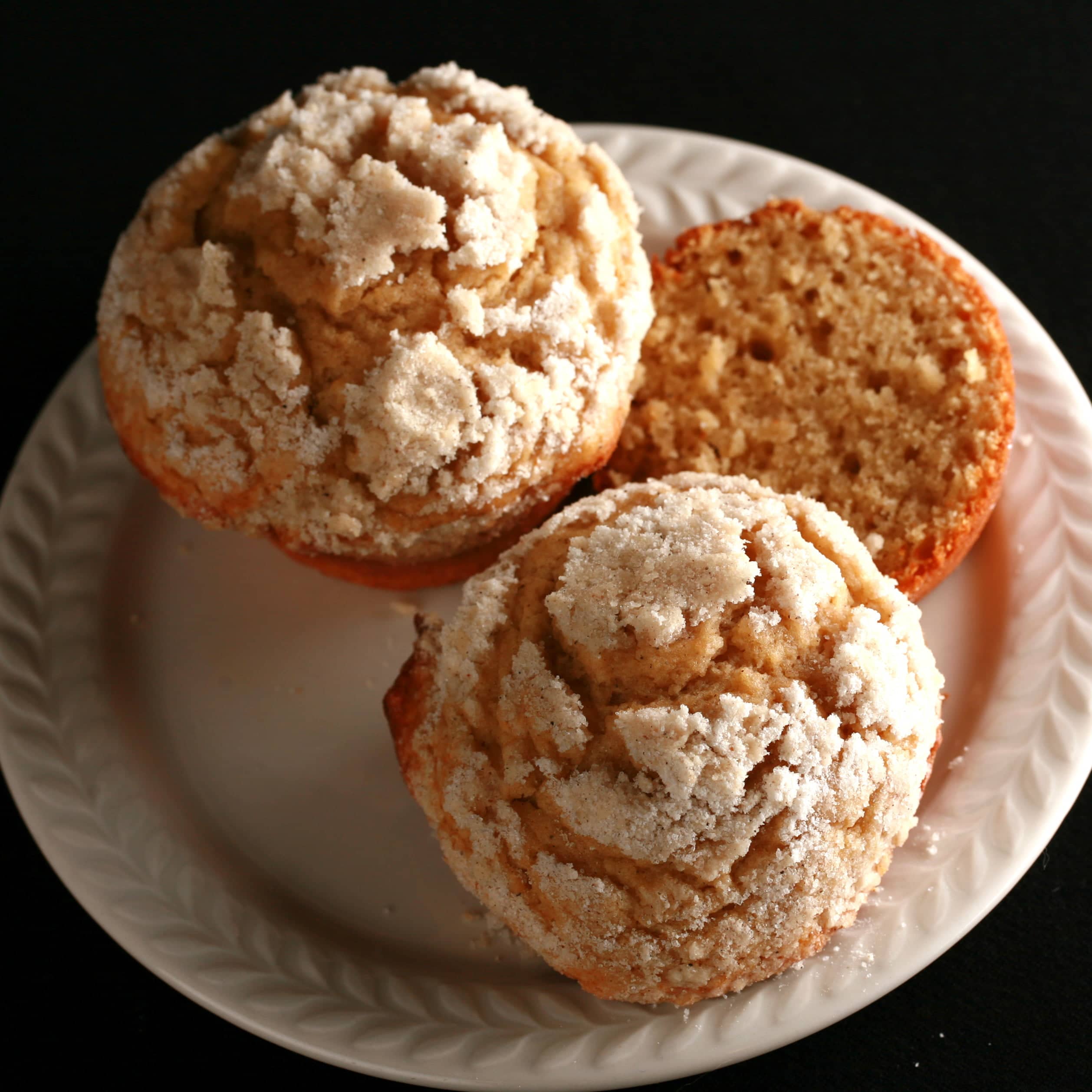 Two cardamom pear streusel muffins on a small white plate.