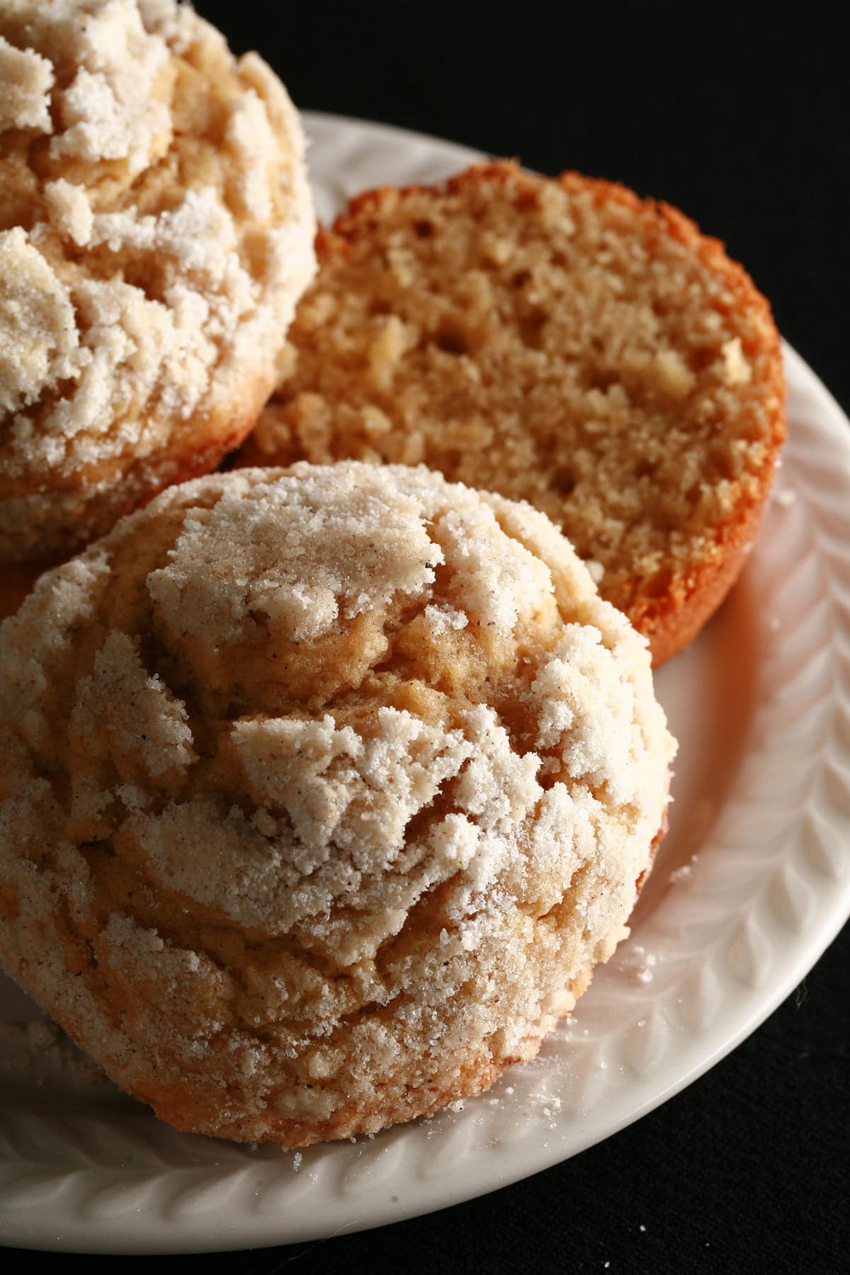 Two cardamom pear streusel muffins on a small white plate.