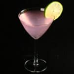 The Drinking In LA - a light pink fizzy cocktail in a martini cocktail glass. It is garnished with a slice of lime.