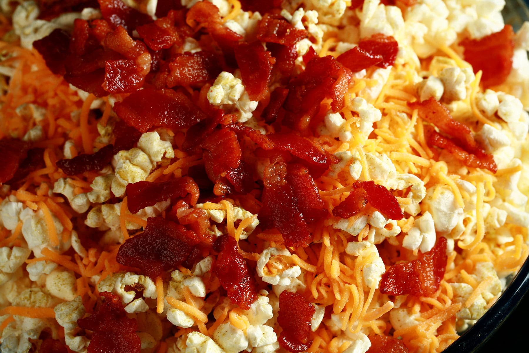 A close up view of Porter's Epic Popcorn - Popcorn with bacon, cheese, and jalapeno powder on it.