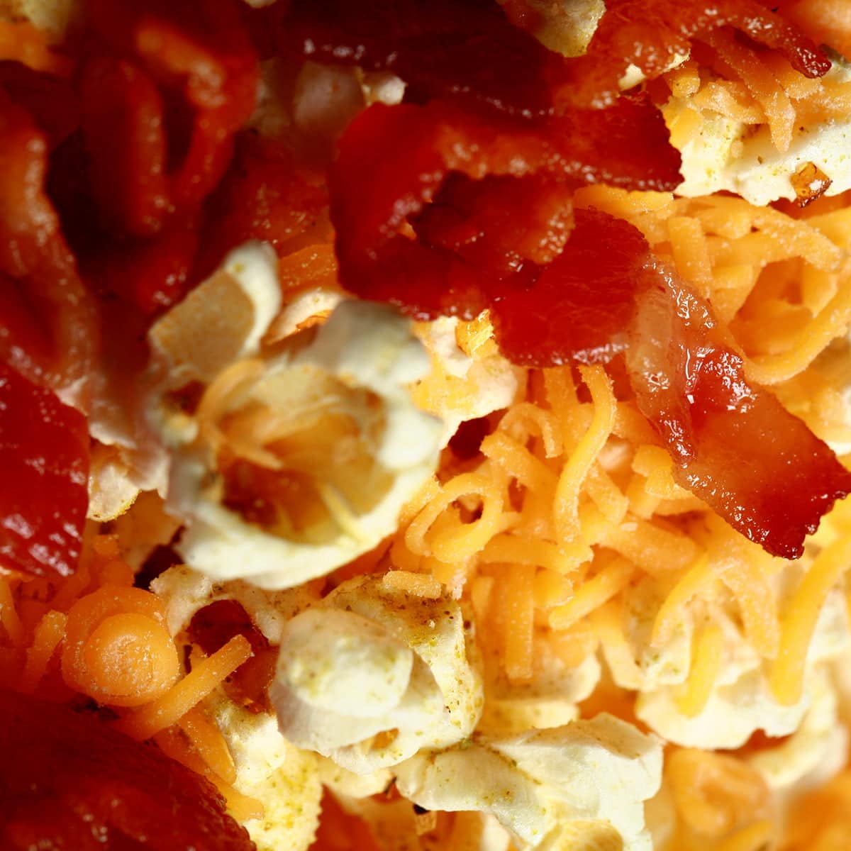 A close up view of Porter's Epic Popcorn - Popcorn with bacon, cheese, and jalapeno powder on it.
