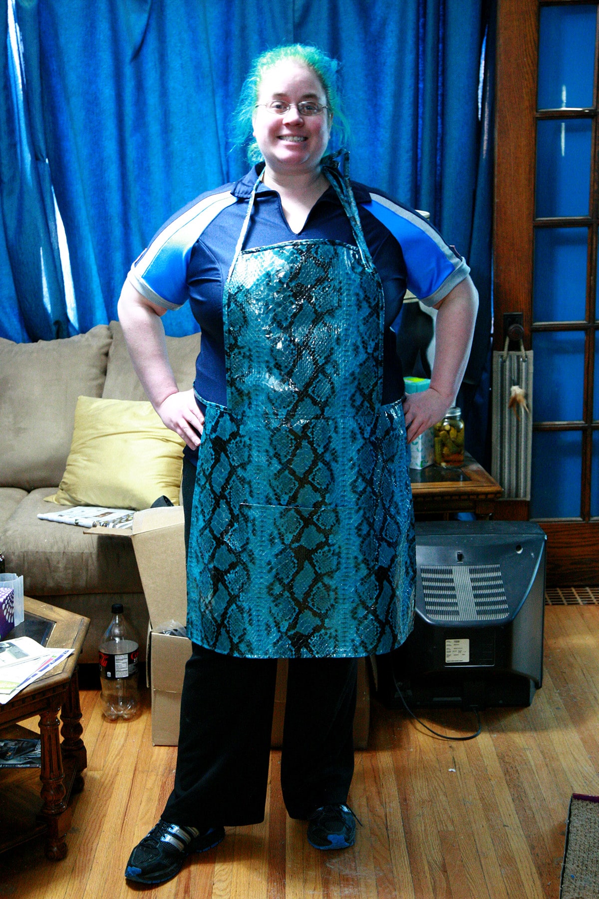 A blue haired woman wearing a blue snakeskin print apron.