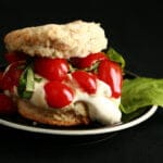 Savoury Tomato Shortcake: A baking powder biscuit "sandwich" on a small black plate. The biscuit has soft white cheese, cherry tomatoes, and fresh basil as its filling.