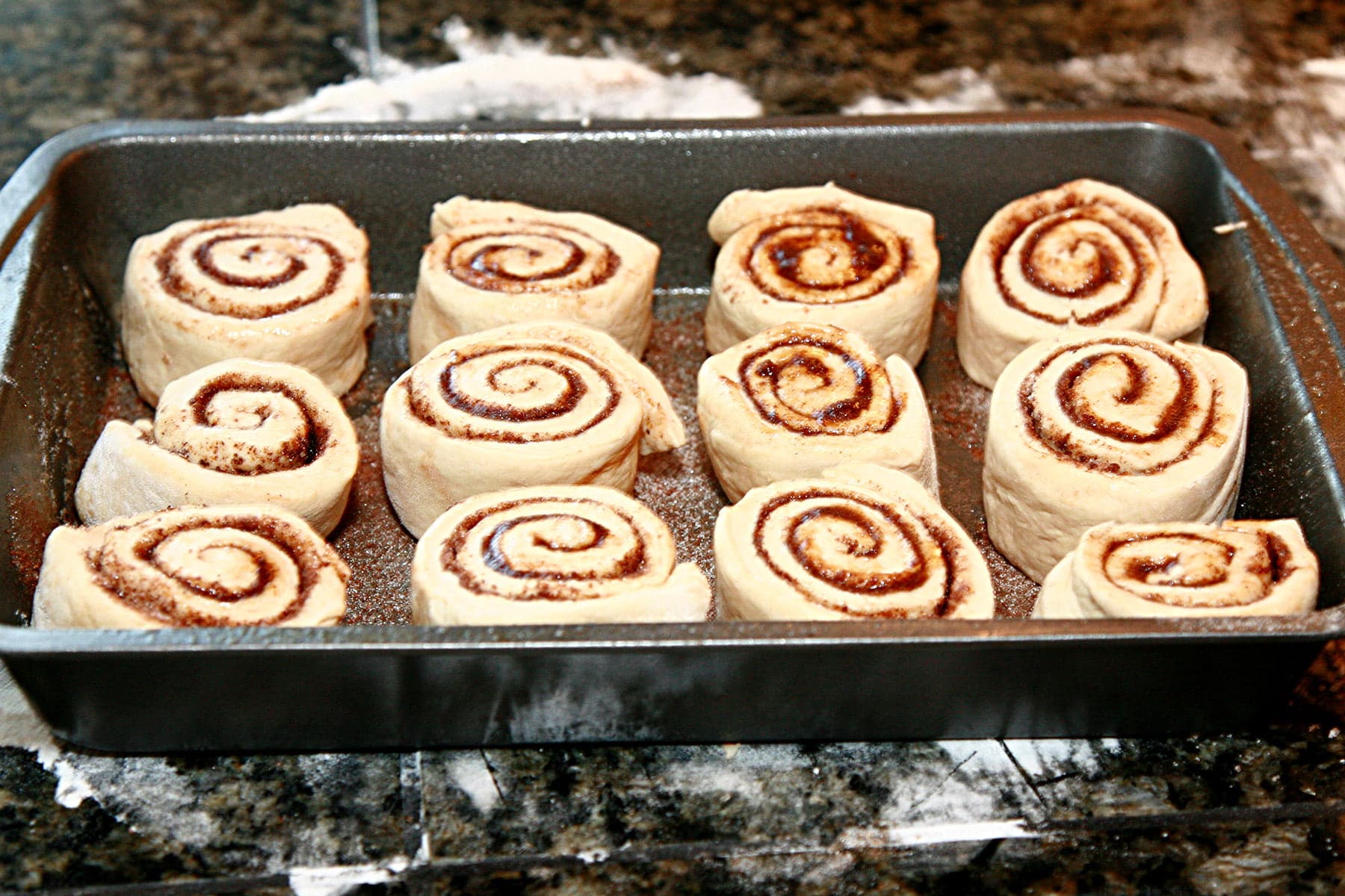12 unbaked chai rolls, resting in a baking pan.