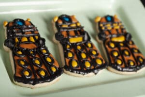 3 decorated Dalek sugar cookies on a light green plate.