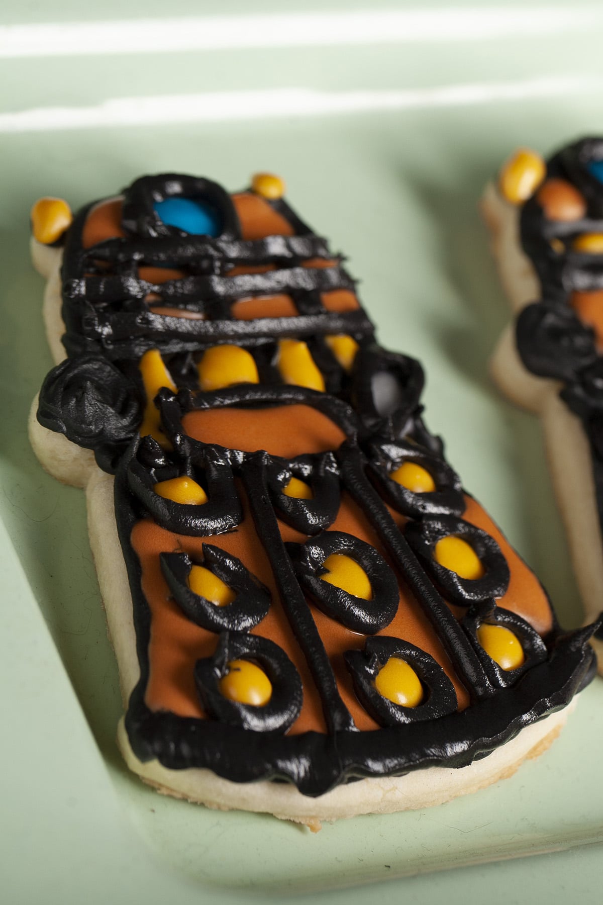 3 decorated Dalek sugar cookies on a light green plate.