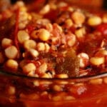 A close up view of roasted corn salsa for canning - corn salsa with tomatoes and peppers - in a glass bowl.