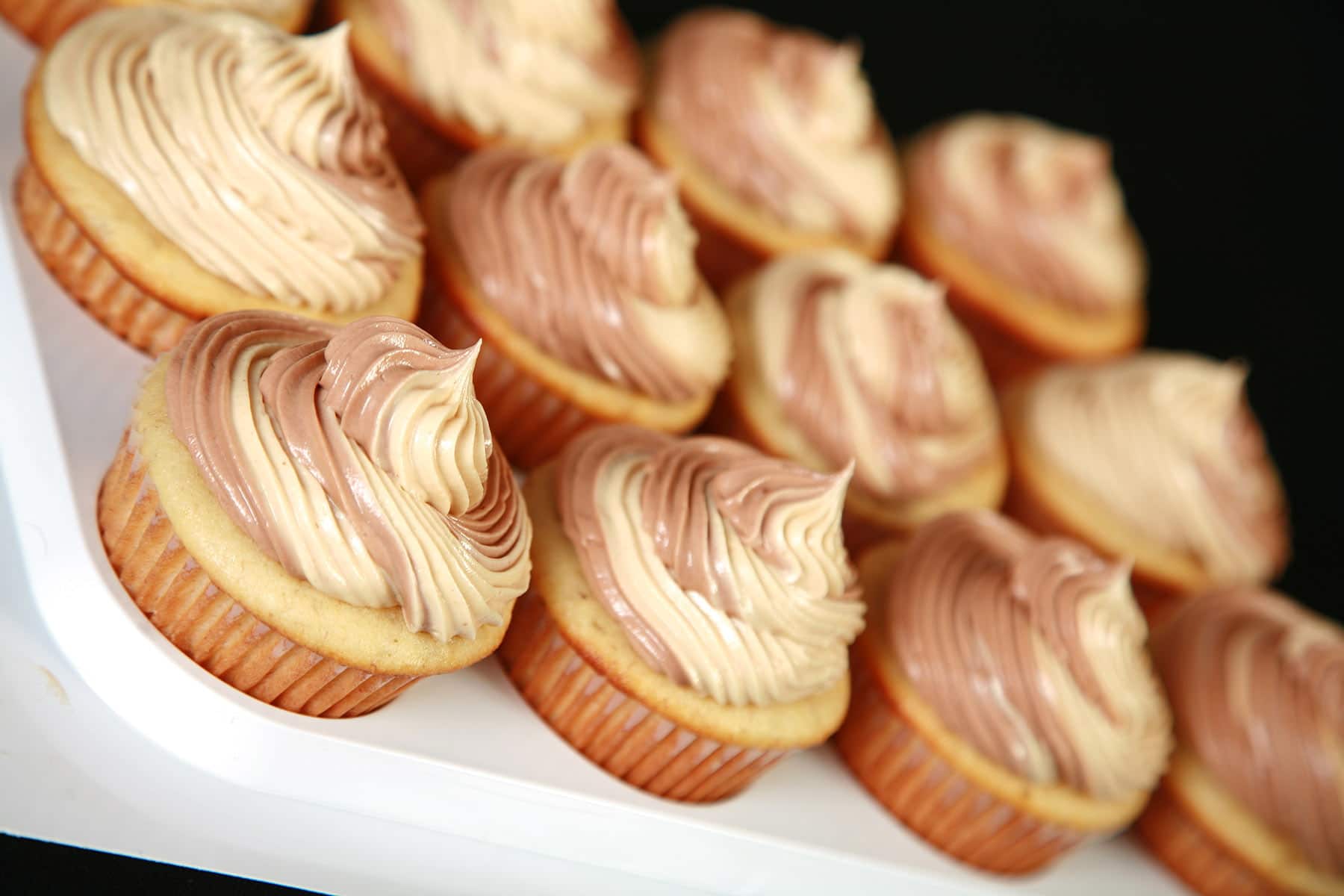A tray of Fat Elvis Cupcakes - Banana cupcakes frosted with a two-tone swirl of Swiss Meringue buttercream, in both peanut butter and chocolate flavours.