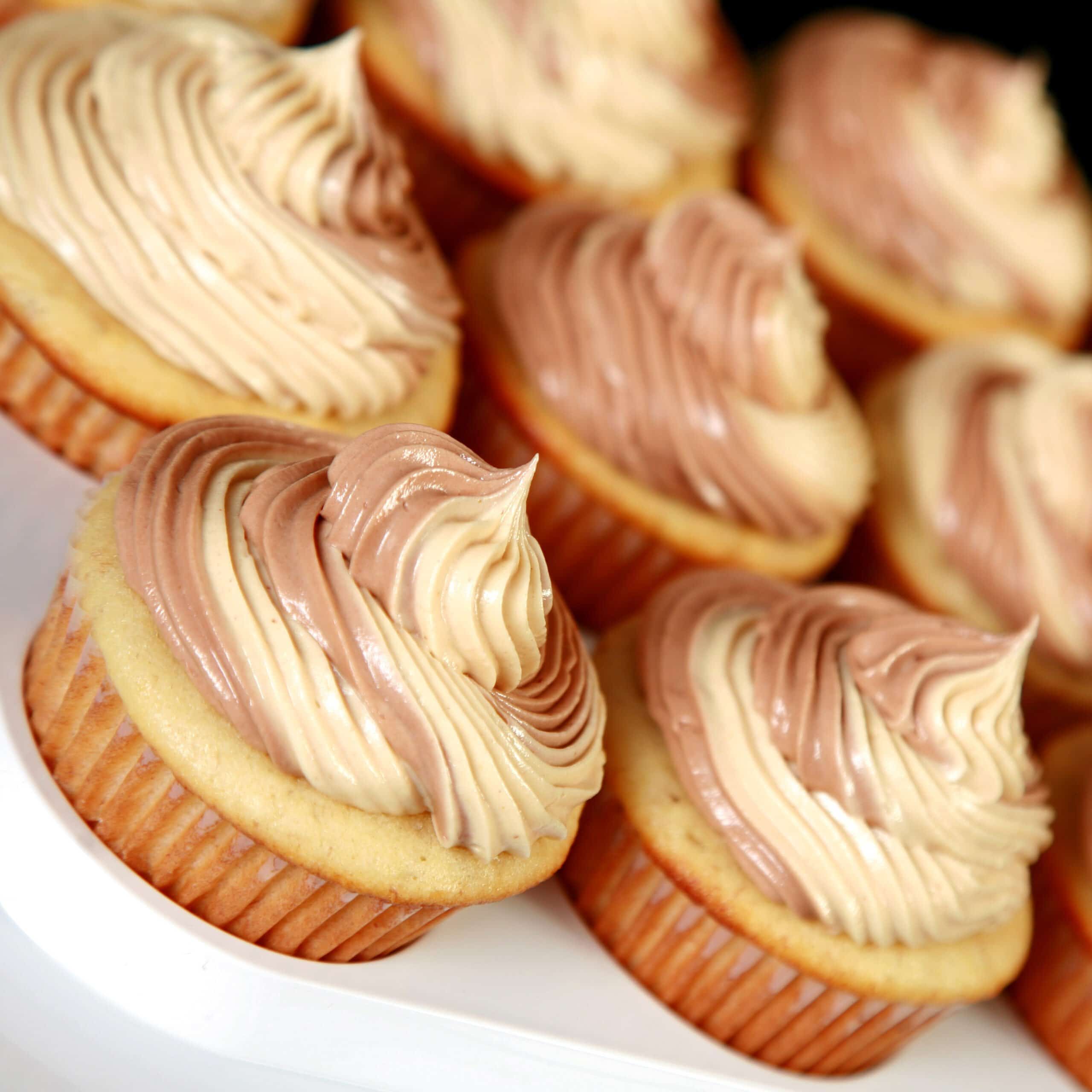 A tray of Fat Elvis Cupcakes - Banana cupcakes frosted with a two-tone swirl of Swiss Meringue buttercream, in both peanut butter and chocolate flavours.