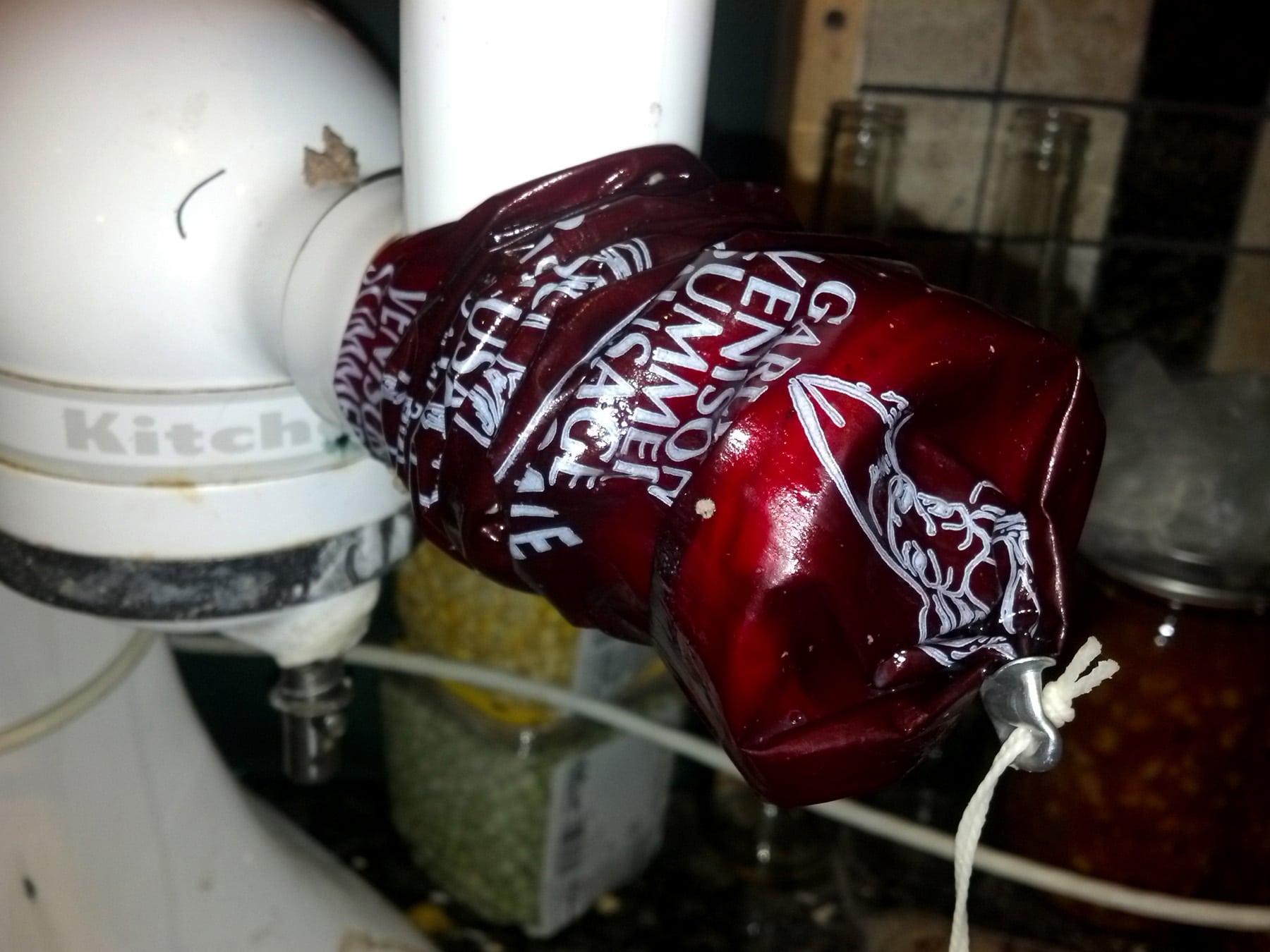 A red sausage casing being fed onto a kitchenaid stand mixer.