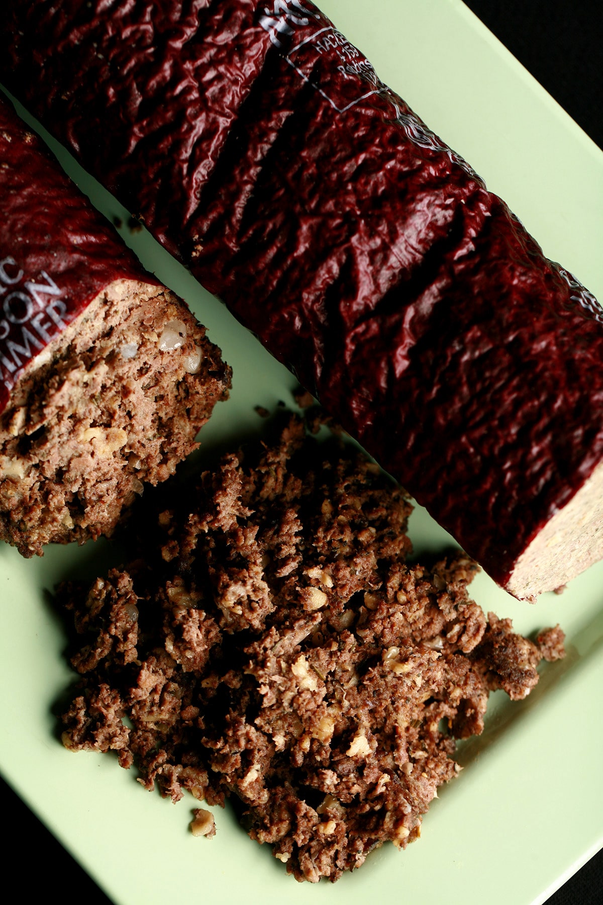 A green plate with a log of haggis "sausage", along with some loose haggis next to it.