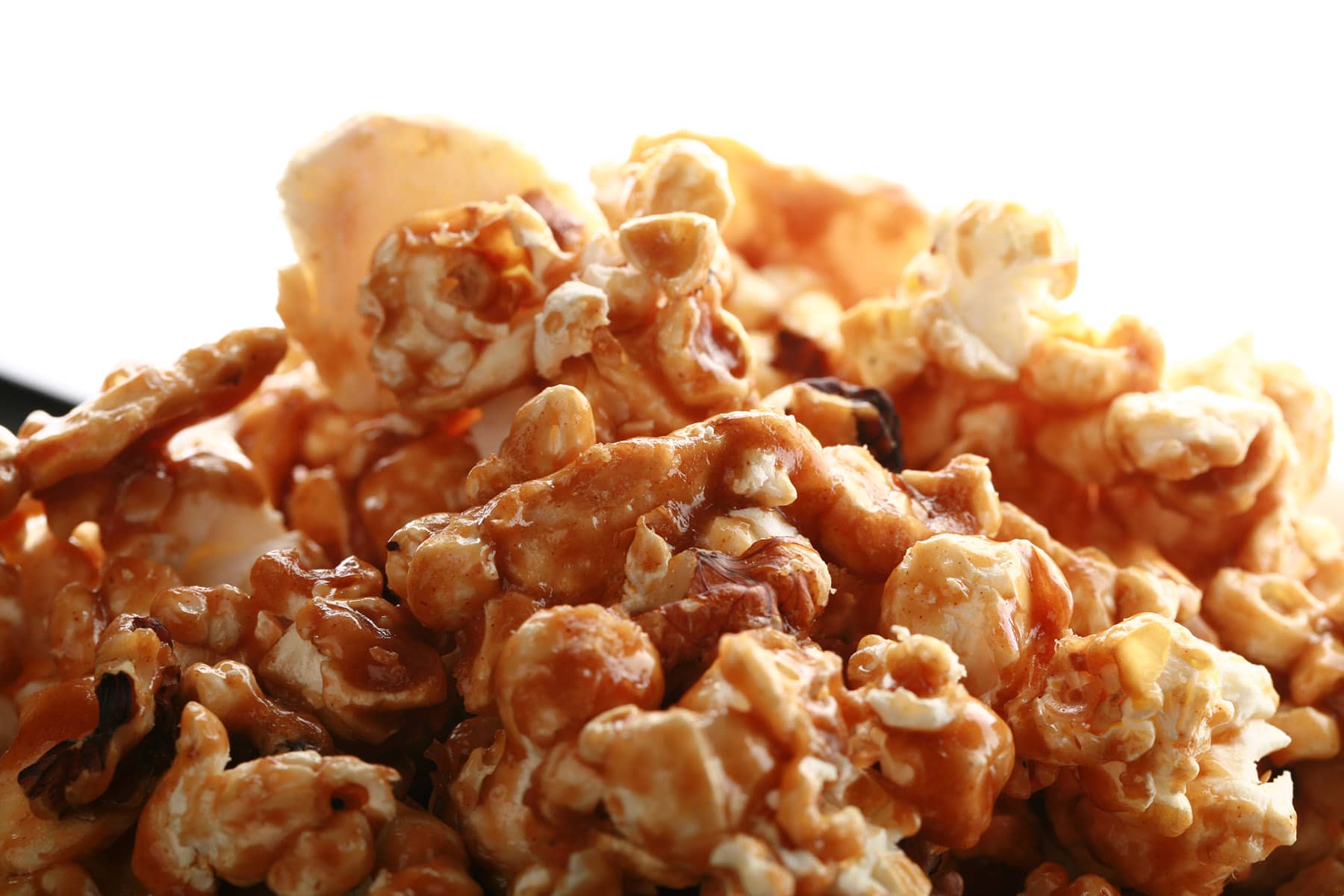 A close up view of a bowl of caramel popcorn with dried apples and cinnamon.