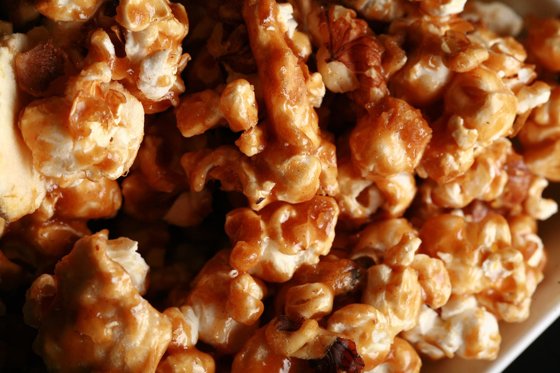A close up view of a bowl of caramel popcorn with dried apples and cinnamon.