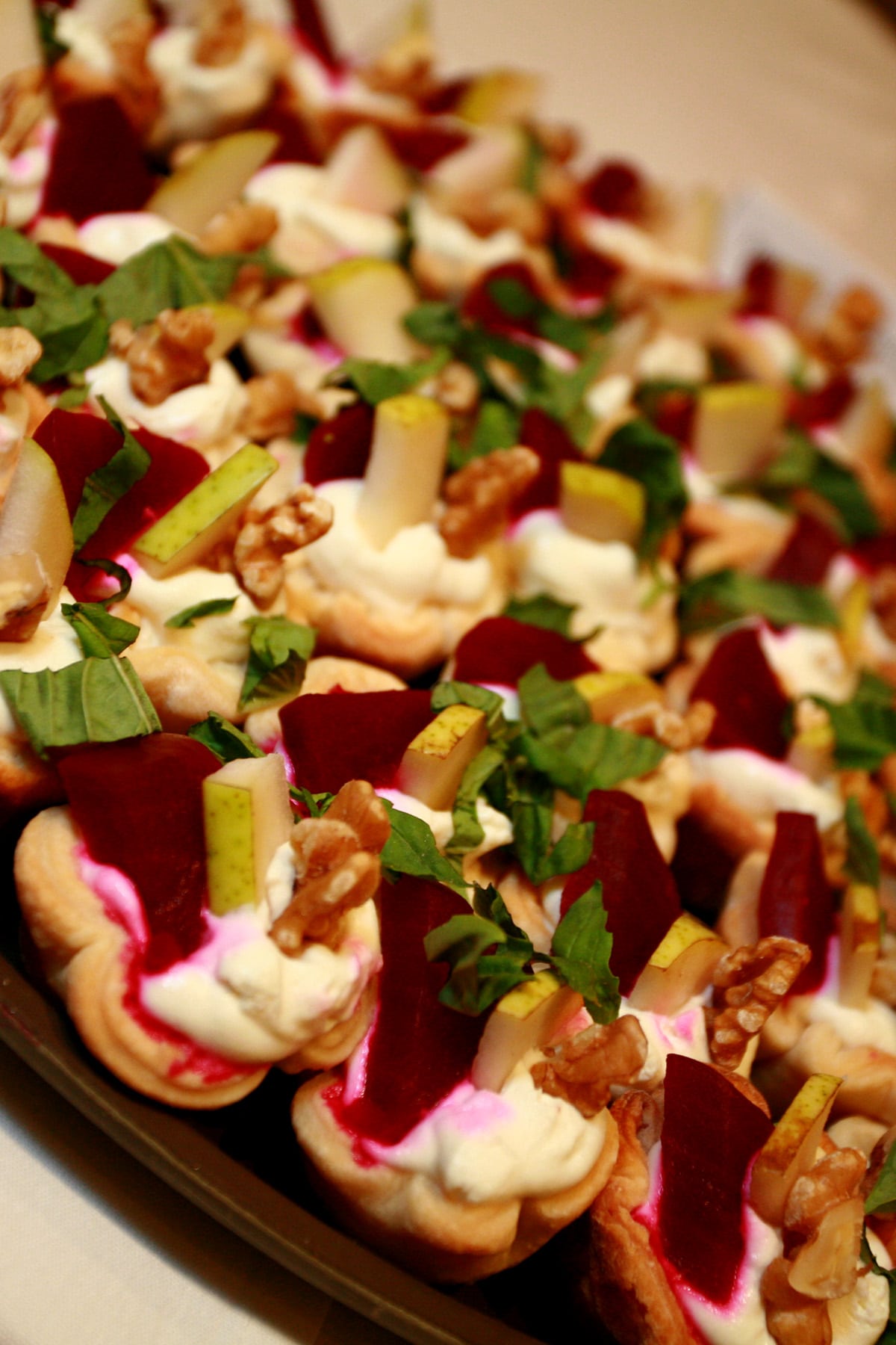 A close up view of mini beet salad tarts on a platter.