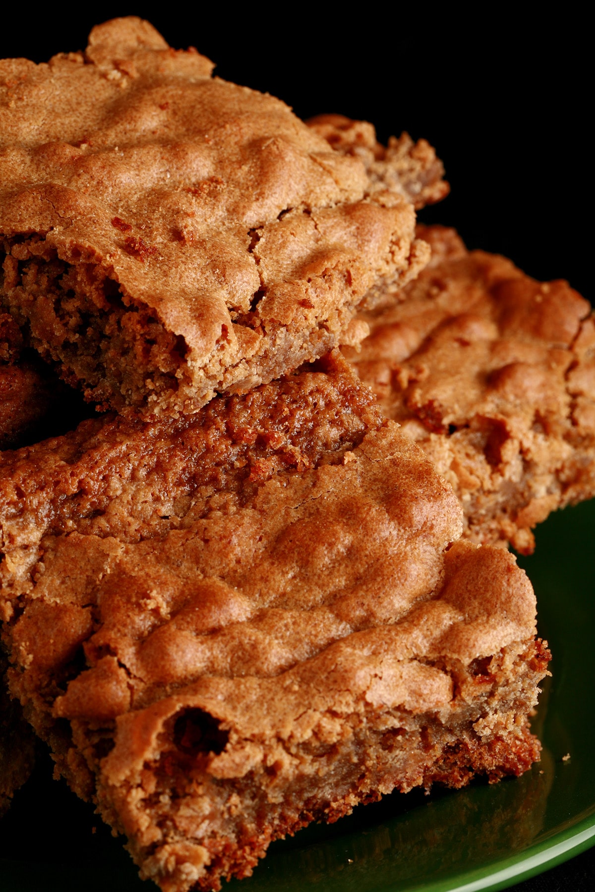 Several chewy chai blondies stacked on a small green plate.