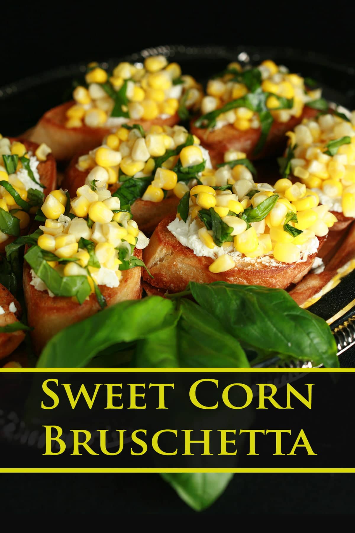 A silver, oval shaped platter, filled with sweet corn bruschetta - slices of toasted baguette, smeared with goat cheese, and topped with sweet corn kernels, basil, and balsamic vinegar.