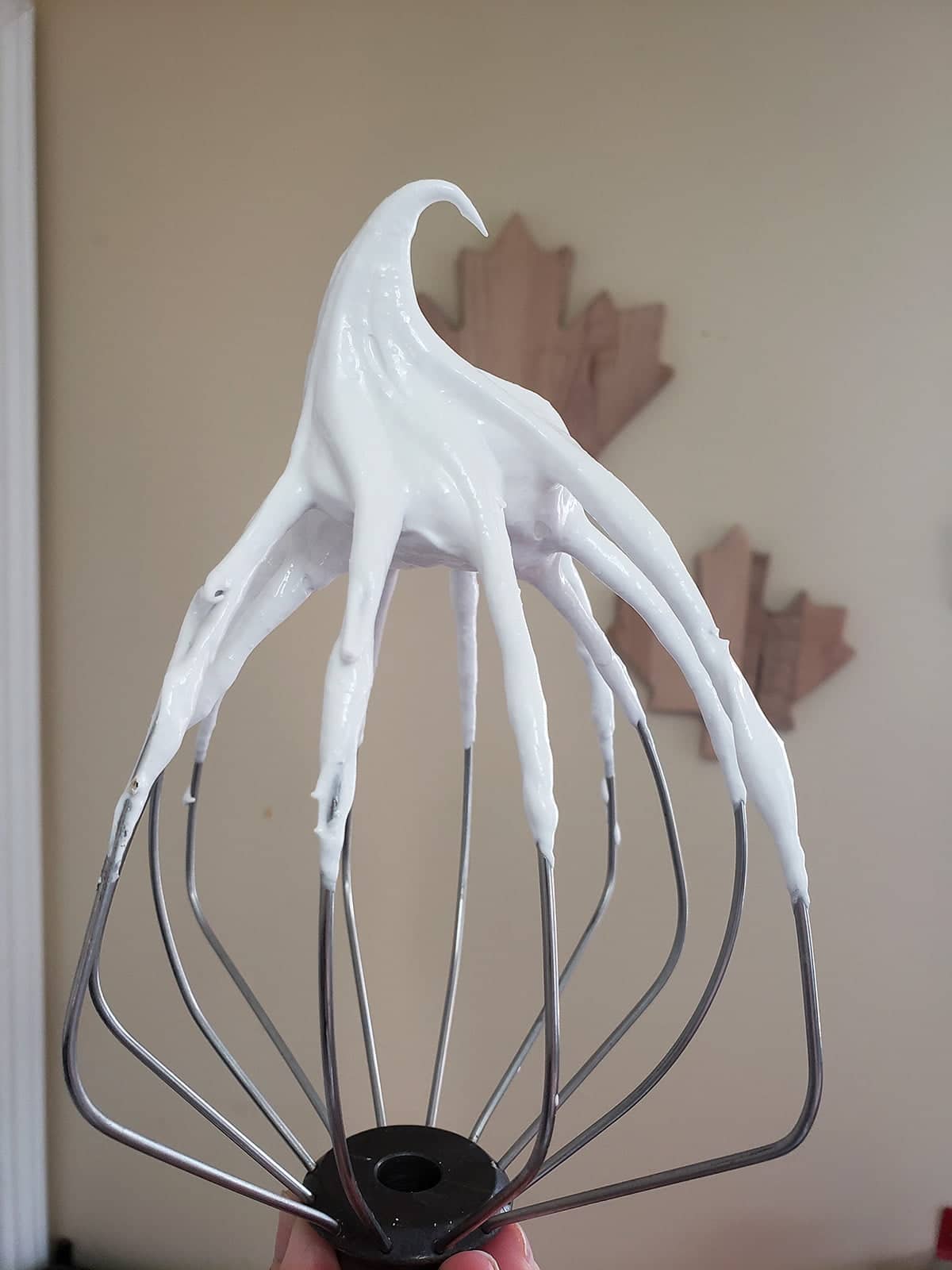 An inverted whisk with a soft peak of meringue on top.