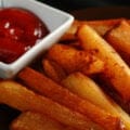 A plate of smoked fries, with a small bowl of ketchup on the side.