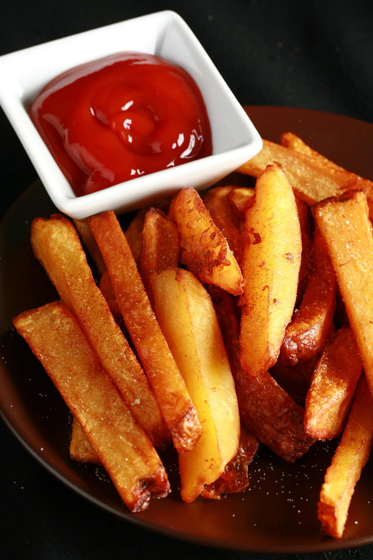 A plate of smoked french fries, with a small bowl of ketchup on the side.