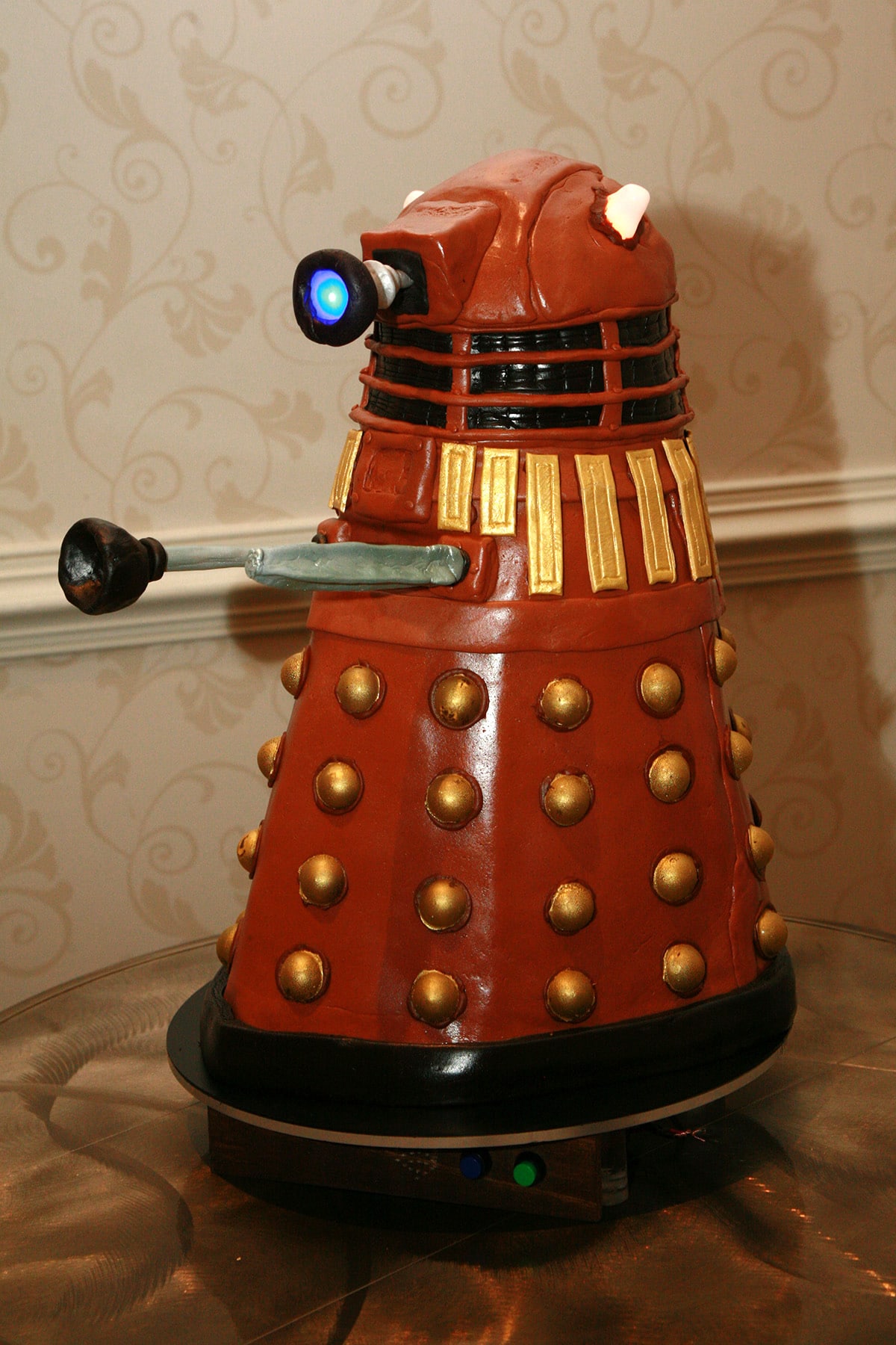 A brown Dalek cake on a hotel table.